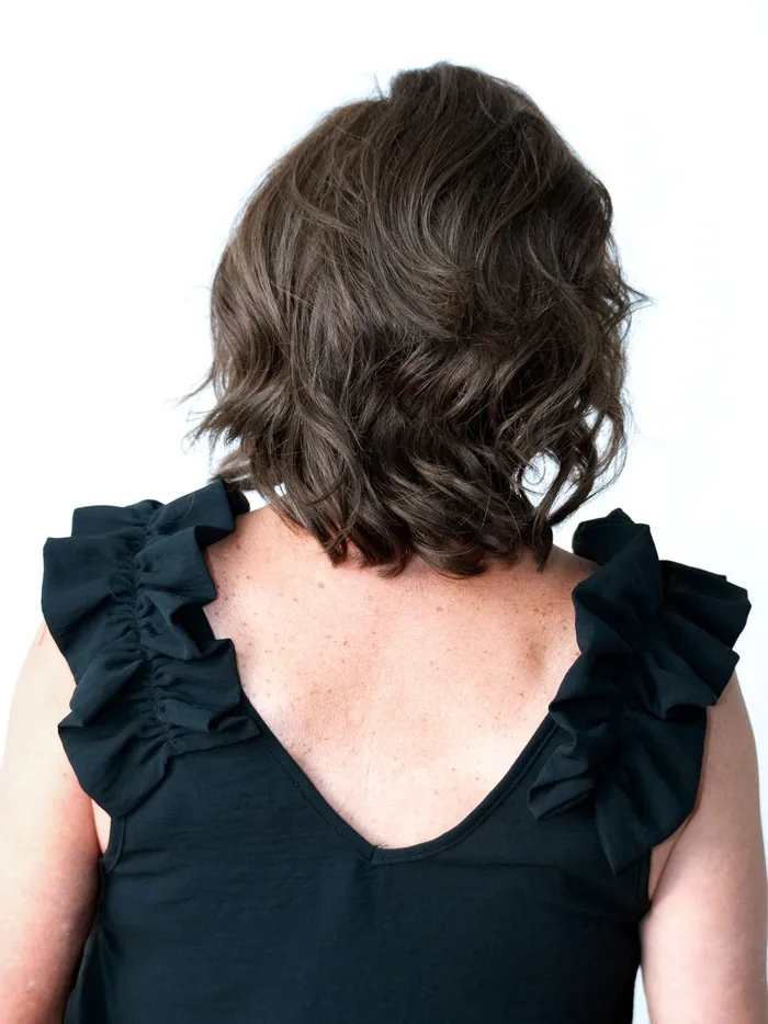 Back of the head view of a finished layered brown hair system showing full coverage at the crown and nape