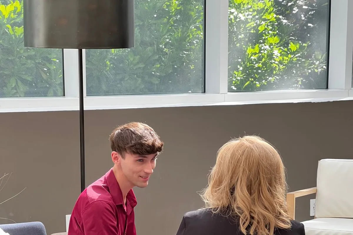 A specialist and a client seated facing each other on low couches in a bright lounge, mid conversation