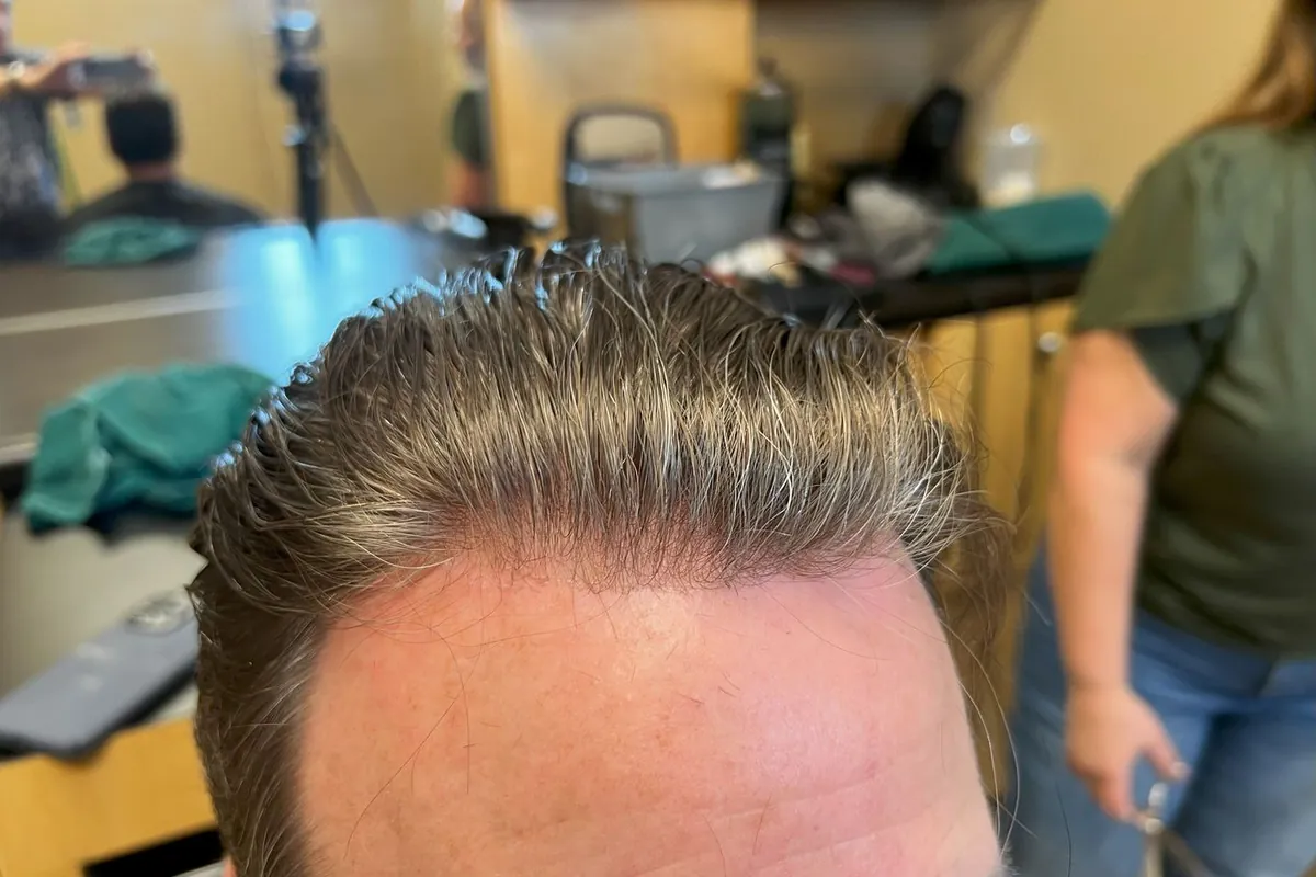 Close top-down view of a finished part line and front hairline on a styled hair system