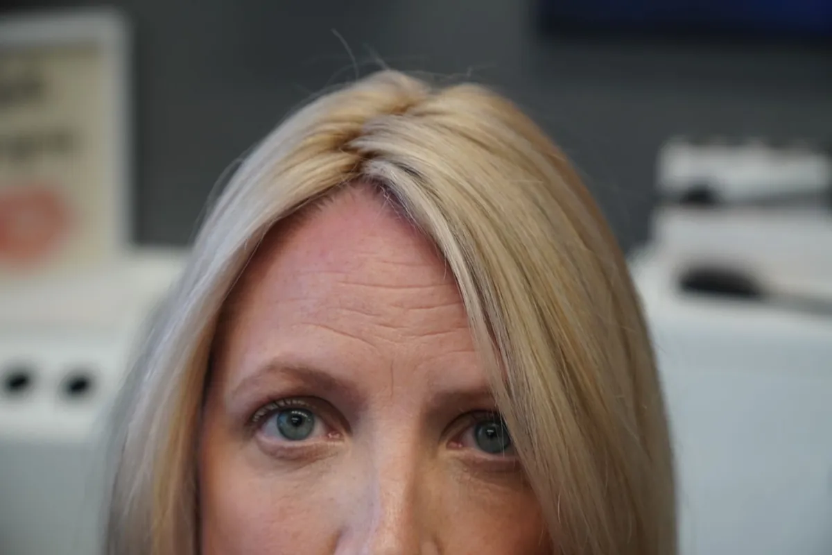 Client seated at an evaluation station looking toward the specialist, with equipment softly out of focus behind her