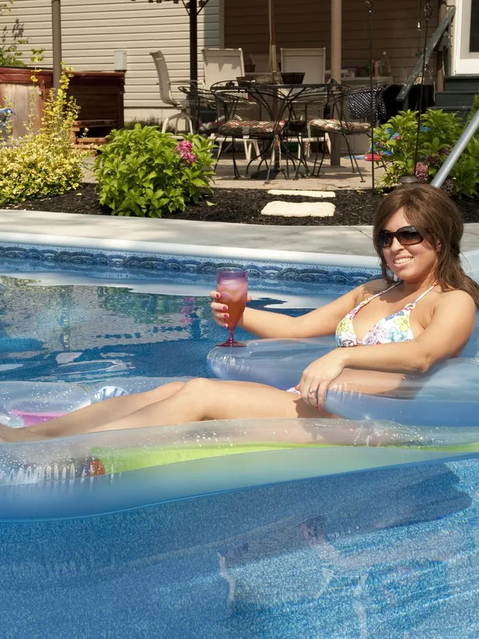 Client floating on a pool raft in sunglasses with her hair down