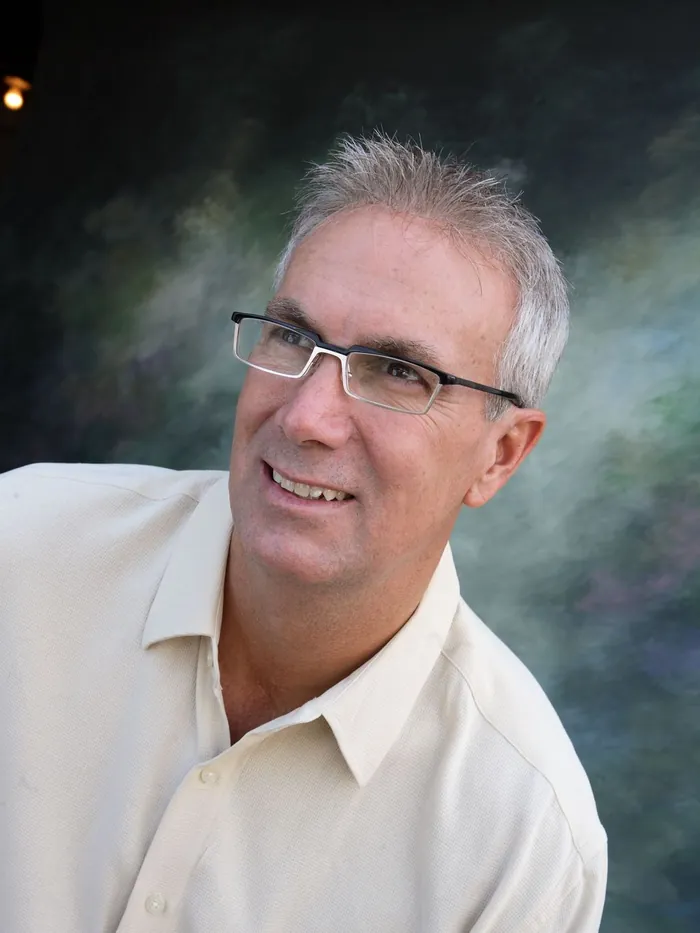 White and silver mens hair replacement system on a client with glasses, three-quarter view